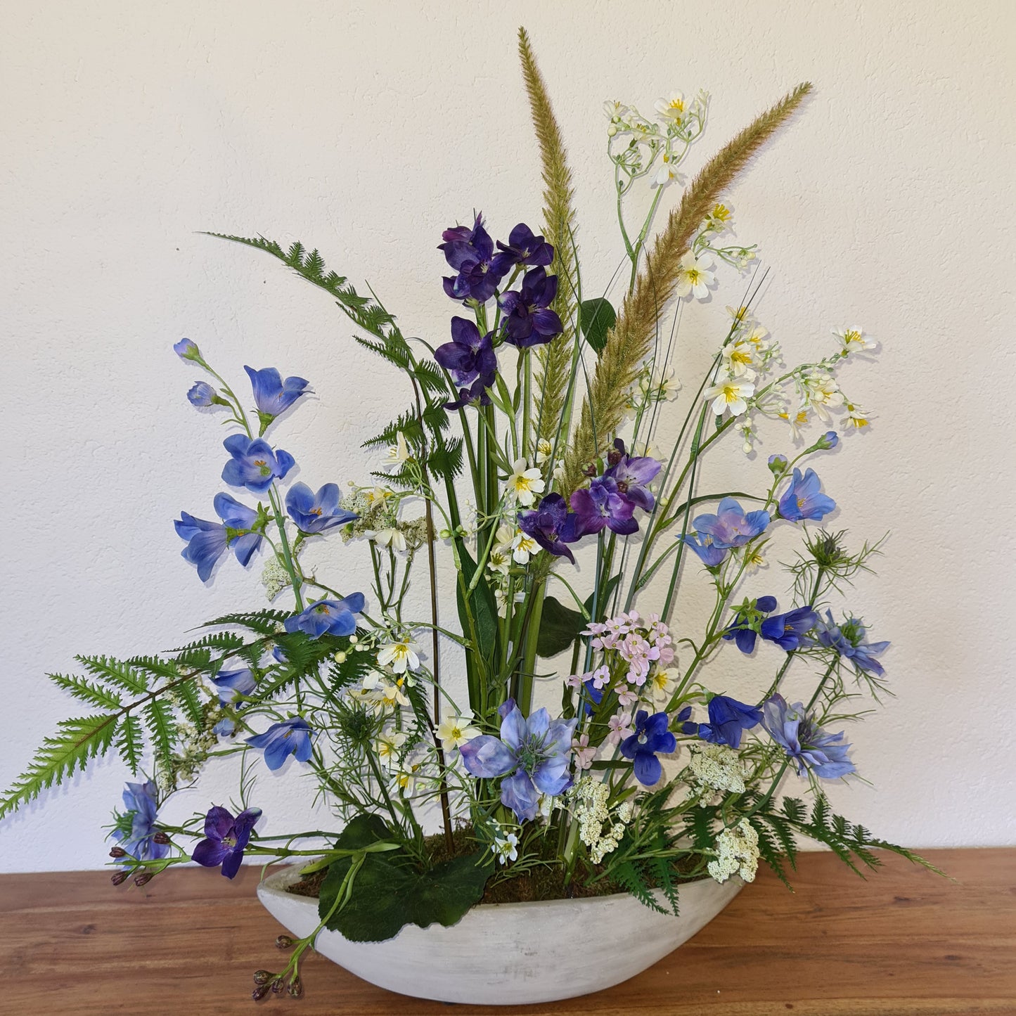 Gesteck mit Wiesenblumen in Beton Schiffchen